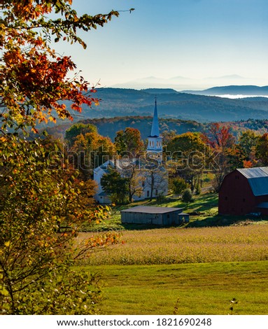 Peacham Congregational Church and a farm with red barn.  The church is the Olde Meeting House in the Village, Peacham, VT