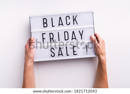 Woman hands holding lightbox with words Black Friday Sale on white background. Top view flat lay