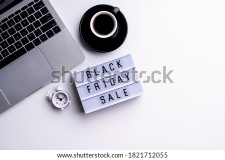 Black Friday Sale words on lightbox with cup of coffee, laptop and clock top view flat lay on white background with copy space