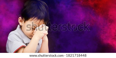 Little toddler boy keep praying for world pandemic coronavirus Covid-19 black banner background.Stay at home praying to GOD.Online church worship in sunday.Hands praying at home.Religion, Christian.