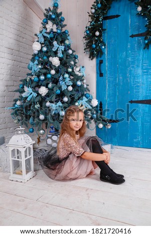 a cute little girl in a dress getting ready for New Year's. Decorating the Christmas tree and checking the gifts
