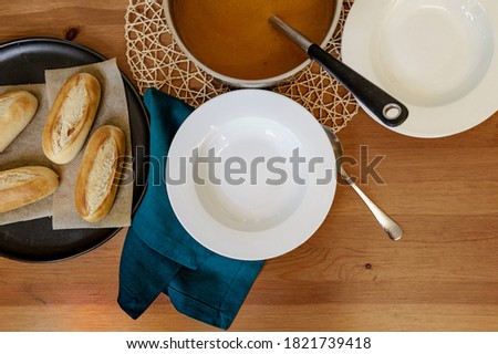 Top down photo of homemade tomato soup being served into bowls on wooden table
