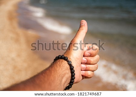 A man's hand on the background of the sea surf. Gesticulation.Different hand movements.