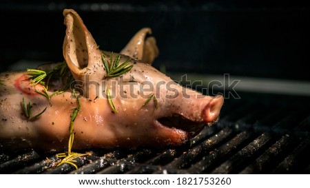 Tasty pork on a barbecue grill. Close up of whole pig cooked grilled meat in BBQ of garden home at holiday vacations. Crispy roasted piglet on a spit in Spain.