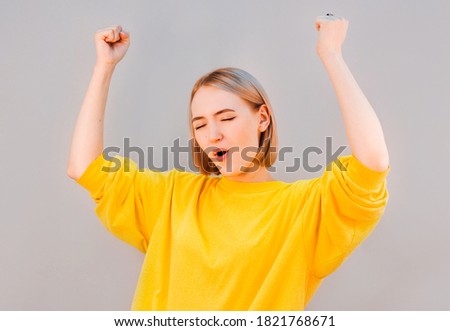 Pretty blonde woman cheering against gray background