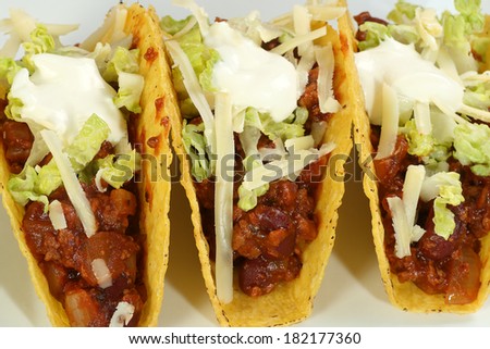        three mexican tacos with minced beef and sour cream topping                        