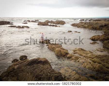 Girls standing on rocks at Asilomar Beach in California