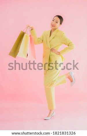 Portrait beautiful young asian business woman with shopping bag on color isolated background