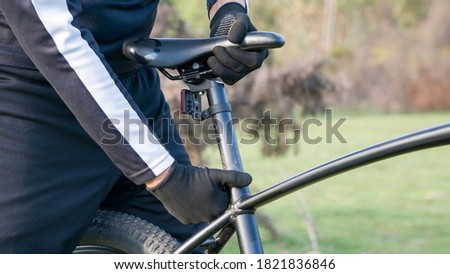 cyclist with black gloves adjusting black seat Royalty-Free Stock Photo #1821836846