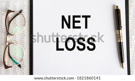 The inscription on the tablet with a fixed sheet of paper NET LOSS, next calculator, graphs, reports.