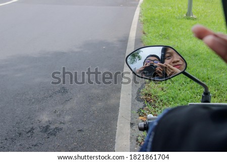 portrait of an asian man and woman holding a camera. take a photo of yourself in the rearview mirror of a motorcycle. togetherness in a romantic and happy relationship while on vacation