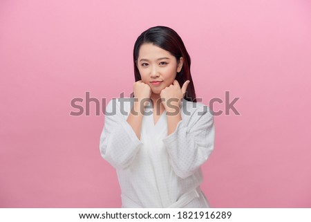 Portrait of young Asian woman smiling friendly with hands on chin