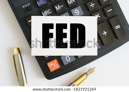 Business and finance concept. On the table there is a pen, a calculator and a business card on which the text is written - FED