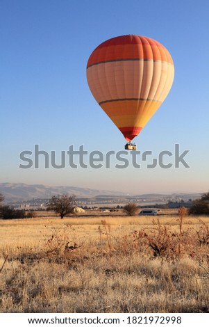 Colourful hot air balloon flying over the yellow filed in Cappadocia Turkey