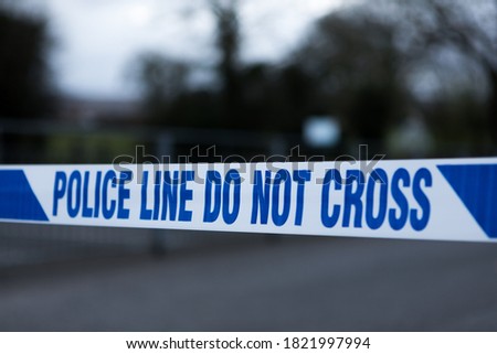 Police barrier tape in the UK at the scene of a crime. Police line do not cross Royalty-Free Stock Photo #1821997994