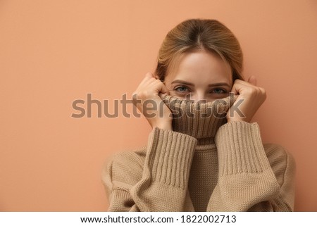 Beautiful young woman wearing knitted sweater on light brown background. Space for text Royalty-Free Stock Photo #1822002713