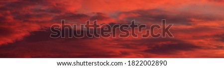 Epic red sunset sky above the sea. Dark glowing clouds. Natural pattern, texture, background, panoramic view. Meteorology, climate change, seasons, heaven, hope, peace concepts