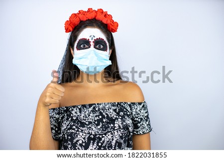 Woman wearing day of the dead costume over isolated white background with mask doing the ok signal with her thumb