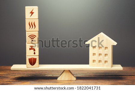 House and blocks with utilities public service symbols on scales. Home is too big and its maintenance costs are high. Availability of bill payment. Improve water and energy efficiency. Energy saving Royalty-Free Stock Photo #1822041731