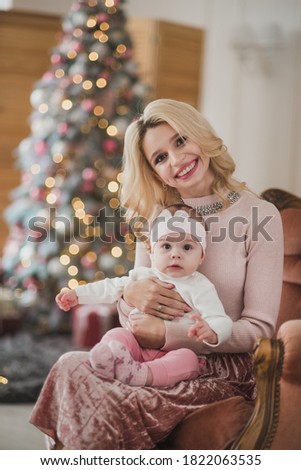 Mother and little girl play near christmas tree in cozy christmas decorations
