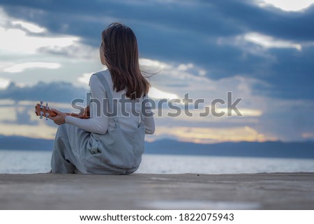 Beautiful woman playing piano by the beach watching sunset