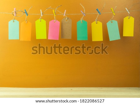Labels in different colors as a background. Rope tags as background. The labels are suspended by a rope on multi-colored clothespins