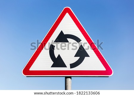 Close-up of roundabout road sign on background of blue sky.