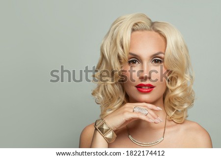 Pretty blonde woman in gold jewelry with diamonds necklace, bracelet and ring, fashion portrait