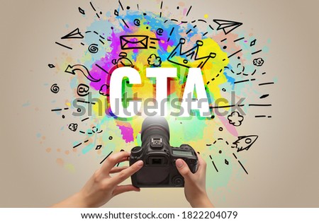 Close-up of a hand holding digital camera with abstract drawing and CTA inscription