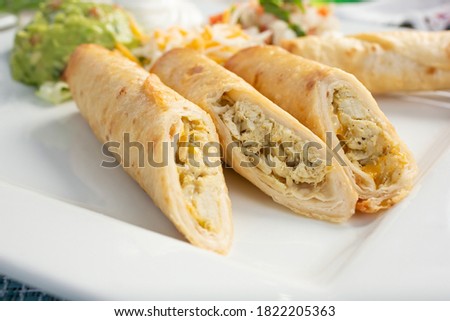 A closeup view of several flautas on a plate.