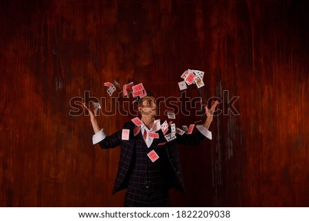 Close-up portrait of young man with gambling cards. Handsome guy shows tricks with card. Clever hands of magician on brown texture background. Concept of entertainment and Hobbies. Copyright space