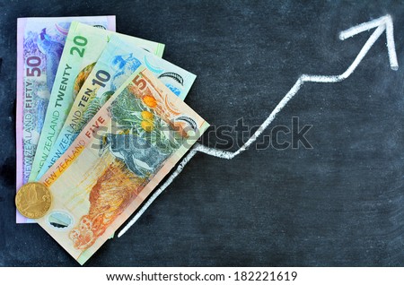 New Zealand Dollar Banknotes on upward trend arrow graph on a blackboard. Concept photo of money, banking ,currency and foreign exchange rates. No people. Copy space