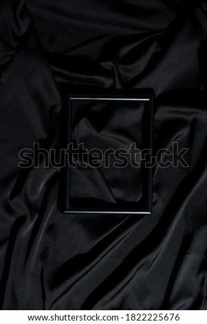 Black decorative photo frame on a dark silk fabric.
