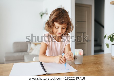 Cute happy little girl, adorable preschooler, 5 years child painting at the table in a white living room at home. Home schooling concept