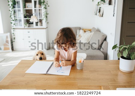 Cute happy little girl, adorable preschooler, 5 years child painting at the table in a white living room at home. Home schooling concept