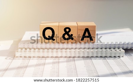Questions and answers concept. Q and A text on wooden cube blocks on table with white financial documents.