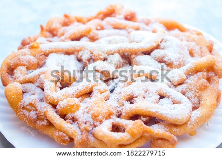 Sweet fried funnel cake, (fried dough) topped with powdered sugar at a summer festival. Royalty-Free Stock Photo #1822279715