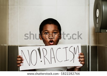 African american boy holding no racism board at toilet in school.No racism No bully at school.Black boy kid during Covid19 coronavirus.Black lives matter activist movement protesting against racism. Royalty-Free Stock Photo #1822282766