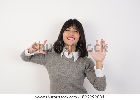 Young  businesswoman with retro short hair wearing casual clothes standing over isolated white background showing and pointing up with fingers number seven while smiling confident and happy.