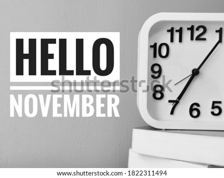 Square shape clock with books and phrase Hello November,banner design.Image may contain noise or grain due to low light.Selective focus.
