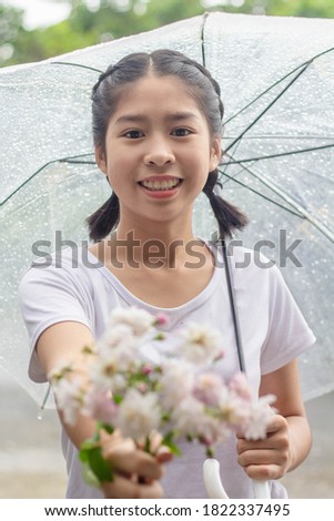 Beautiful Asian teen holding a bouquet of roses and umbrellas.