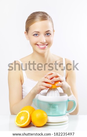 Girl with a juicer and oranges on a gray background