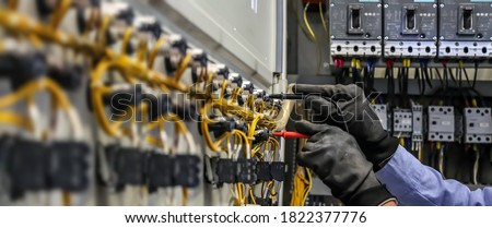 Electrical engineer using measuring equipment to checking electric current voltage at circuit breaker and cable wiring system for maintenance in main power distribution board. Royalty-Free Stock Photo #1822377776