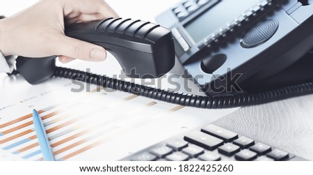 business communications. Finance graphs. Using voip phone. office, close up of hand with receiver. Conference call, contact us or hotline banner. IP telephony, Telemarketing. Help desk call centre