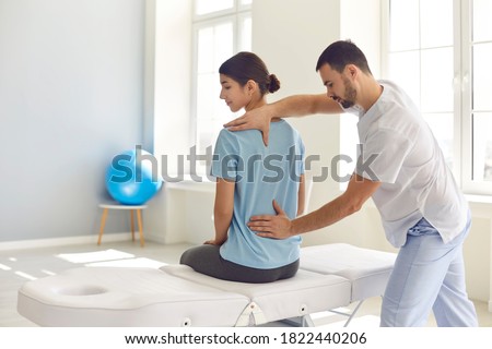 Osteopathic medicine and physiotherapy. Licensed osteopath examining young woman in modern hospital office. Chiropractor helping female patient with scoliosis, low back pain or other spine problems Royalty-Free Stock Photo #1822440206