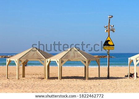 Tsunami warning and evacuation sign located on a beach. The sea and blue sky as background 