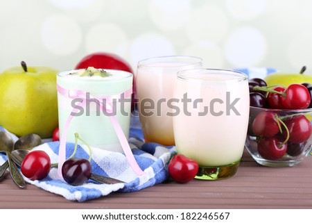 Delicious yogurt with fruits tastes in glasses and fresh fruits on color napkin, on light background
