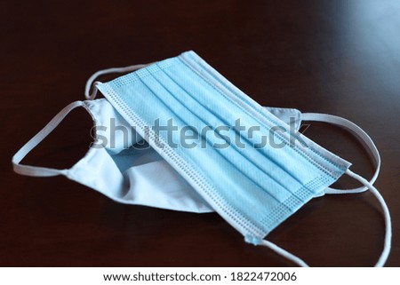 Protective mask on the wooden table General 3 layers mask to cover mouth and nose. (Concept of prevention of respiratory infections) surgical mask with ear band. COVID 19