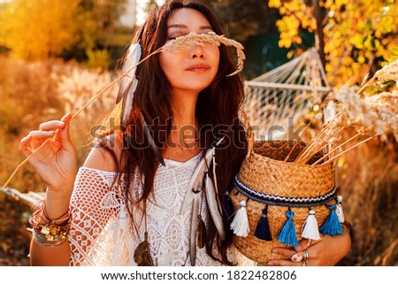 Portrait of a beautiful boho woman in a sunny field at sunset.
