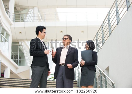 asian business team in conversation with office background